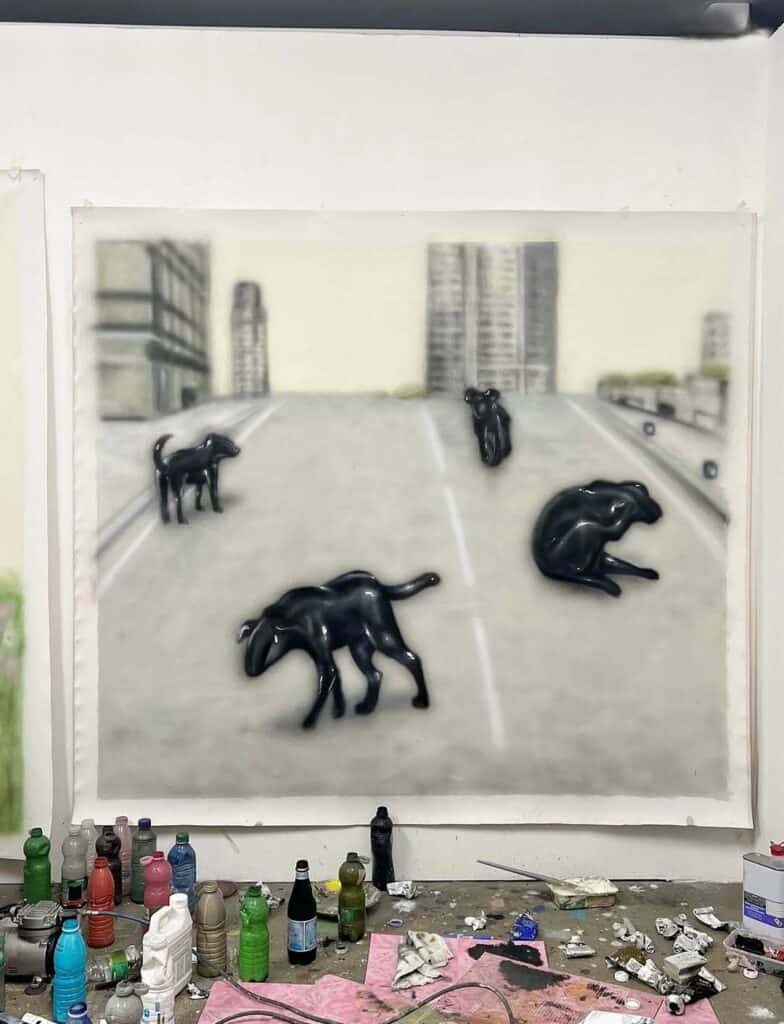 Large painting of glossy black dog-like creatures wandering through an empty urban landscape in Inagaki’s studio.