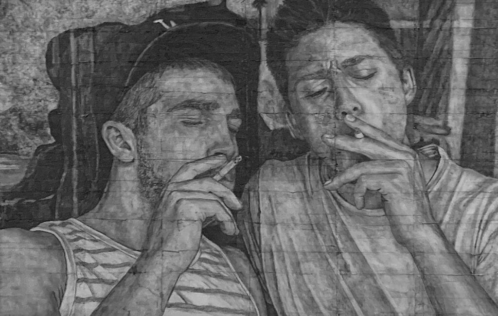 James Robert Morrison’s drawing There is never more than a fag paper between them – Harry and Tom, depicting two men in an intimate moment as they smoke side by side, rendered in soft grayscale pencil on cigarette paper to evoke the fragility of queer visibility.