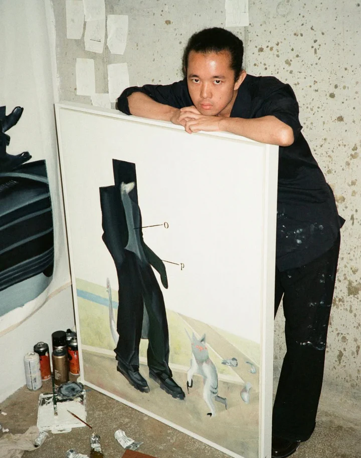 Yutaro Inagaki holding a framed painting featuring elongated black puffer-style humanoid forms and surreal animals.