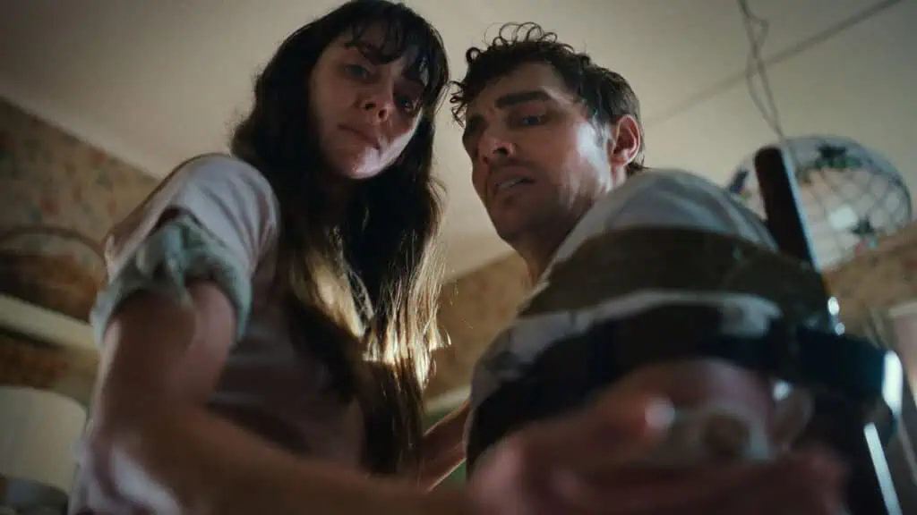 Still from Together (2025) featuring tense scene with two characters, captured from low angle under dramatic lighting.