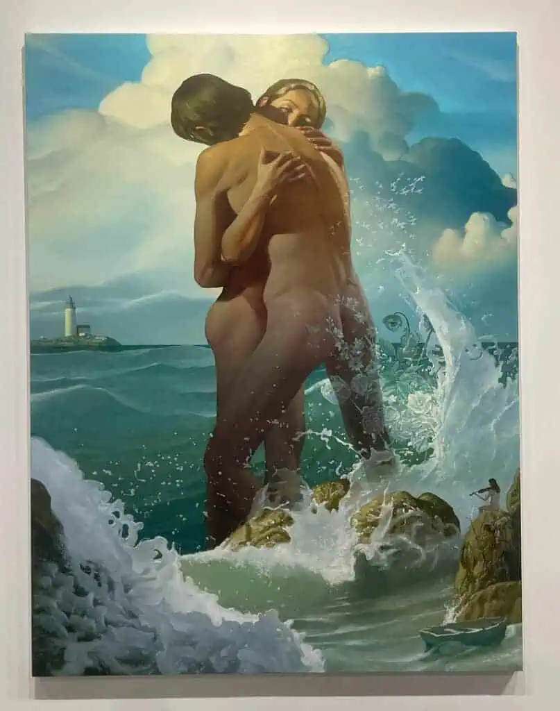 A painting of two nude figures embracing on rocks amid ocean waves, with a distant lighthouse and dramatic clouds. Sunlight highlights their bodies as water splashes around them, capturing the passion and energy of Miami Art Week 2025.