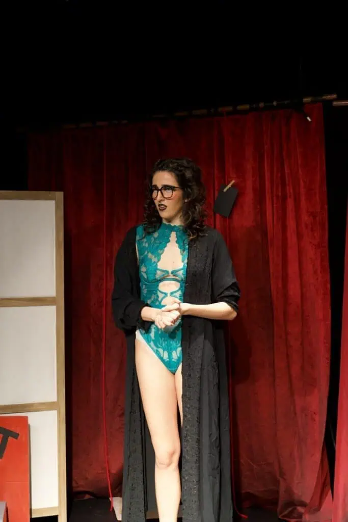 Sofia Natoli in Babel Beast, standing in a teal bodysuit and black robe during her cabaret act.