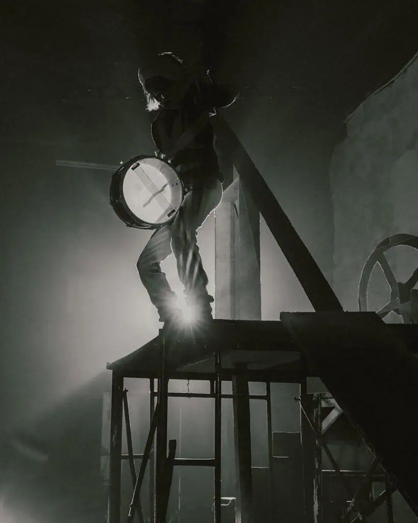 Backlit silhouette standing atop industrial scaffolding, capturing the cinematic tension present in themes surrounding KABEAUSHÉ’s creative world.