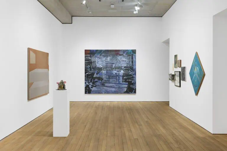 A contemporary art gallery features abstract paintings on white walls, a sculpture of small colorful objects on a pedestal, and wooden flooring under bright lighting as part of Crude Hints Towards curated by Charlotte Edey at Ginny on Frederick for Frieze 2025.