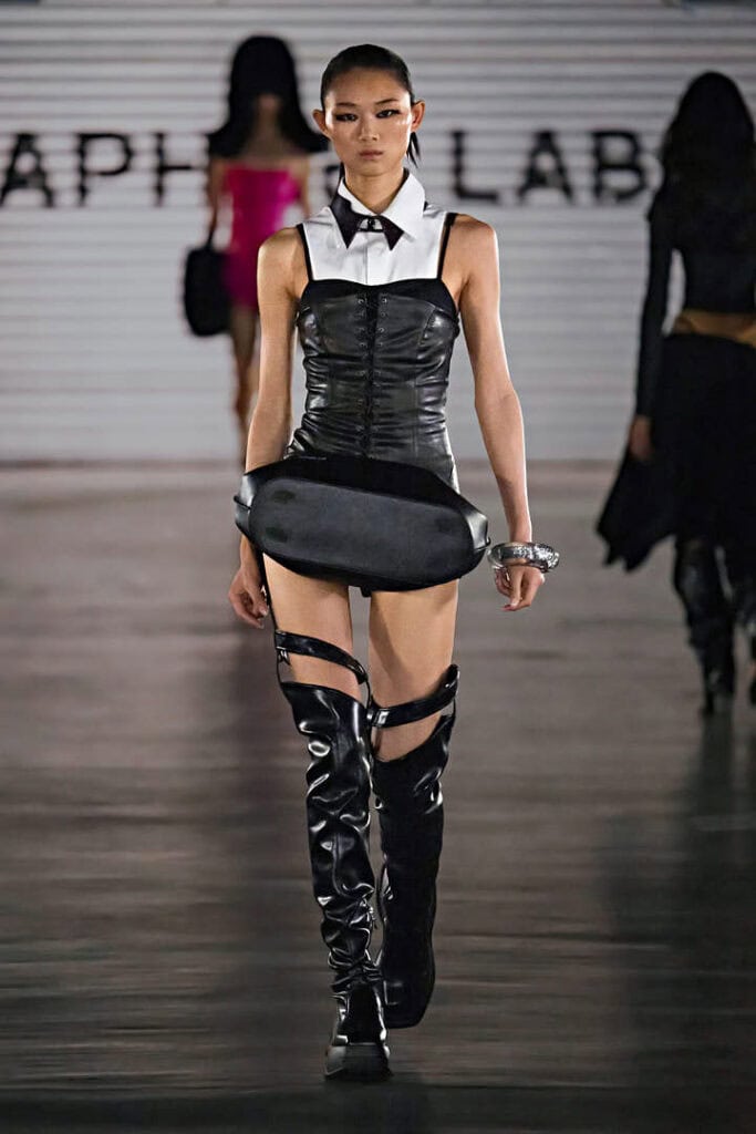Model wearing a black leather corset dress and sculptural accessory belt in the “In a Hurry” collection by Daphne.lab × Marrknull.