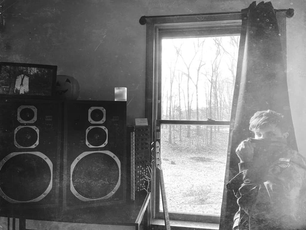 Silhouetted Public Memory figure in a dark, textured room, reflecting ambient and experimental electronic music.