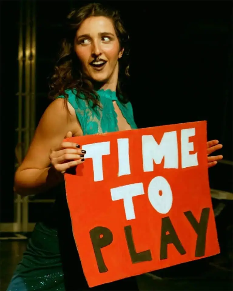 Sofia Natoli performing Babel Beast, holding a red “Time to Play” sign on stage.