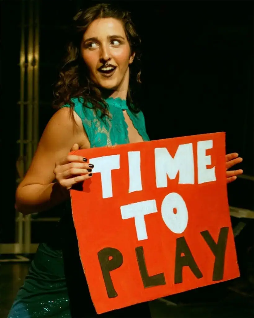 Sofia Natoli performing Babel Beast, holding a red “Time to Play” sign on stage.