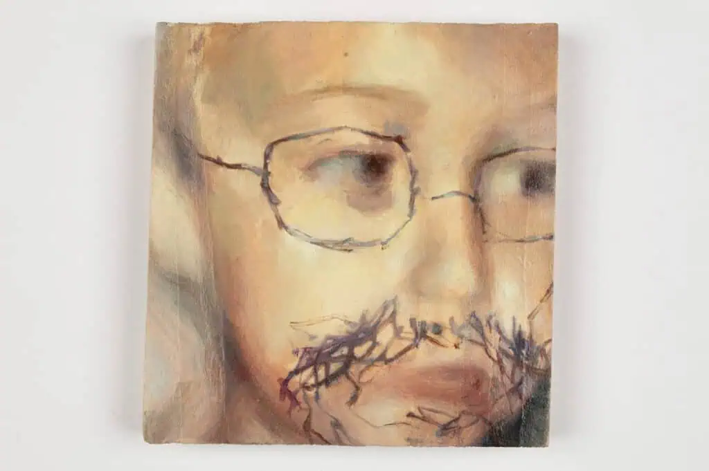 A blurred painting of a person’s face with glasses, overlaid by dark, rough stitched threads forming a mustache and beard, creates a mixed-media effect—perfect for The Hari Art Prize Celebrating London’s Emerging Artists 6.