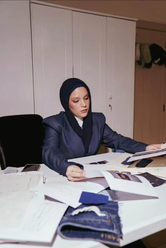 Designer Samah Sulyman reviewing denim sketches and fabric samples in her studio.