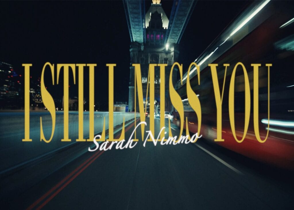 Nighttime city scene under a bridge with blurred lights and a moving vehicle. Large yellow text reads I STILL MISS YOU and smaller white text below says Sarah Nimmo.