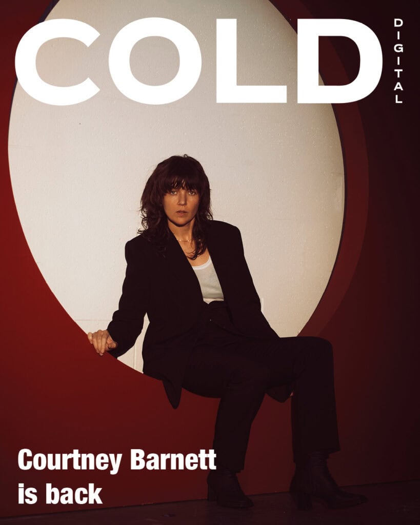 Courtney Barnett on the digital cover of COLD Magazine. The Australian singer-songwriter is sitting inside a red circular architectural frame, wearing a black suit and white top. Text reads "Courtney Barnett is back".
