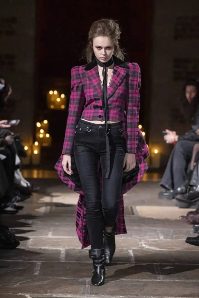 Model wearing a pink and black plaid cropped jacket with a long train by John Richmond