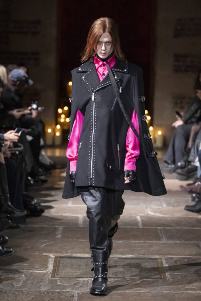 Model showcasing a studded black cape worn over a fuchsia shirt and leather pants by John Richmond