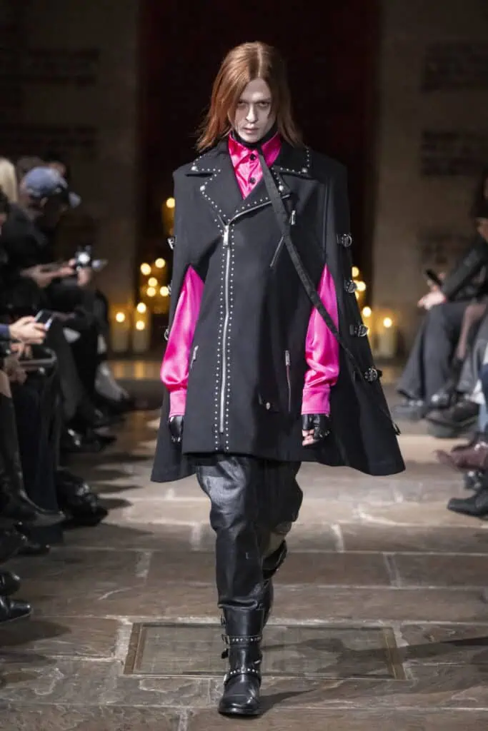 Model showcasing a studded black cape worn over a fuchsia shirt and leather pants by John Richmond