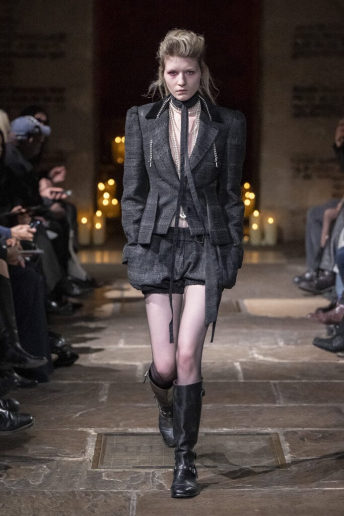 Model wearing a structured grey plaid blazer and matching shorts set by John Richmond