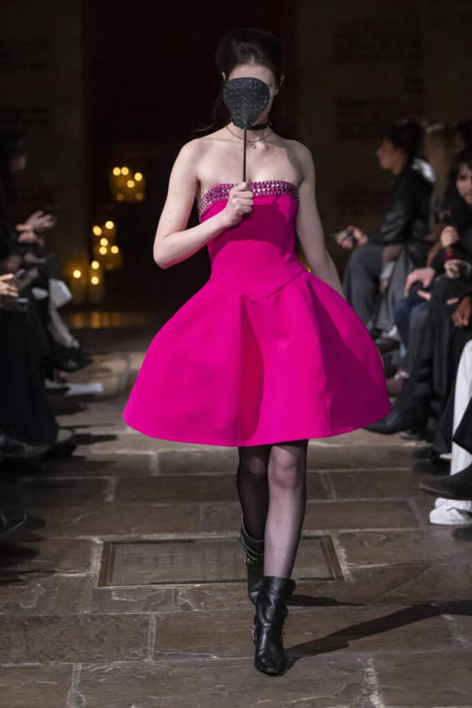Model presenting a vibrant fuchsia strapless mini dress with a full skirt by John Richmond