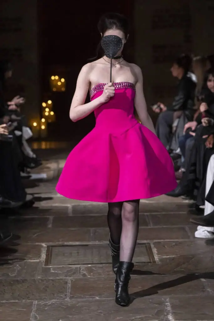 Model presenting a vibrant fuchsia strapless mini dress with a full skirt by John Richmond