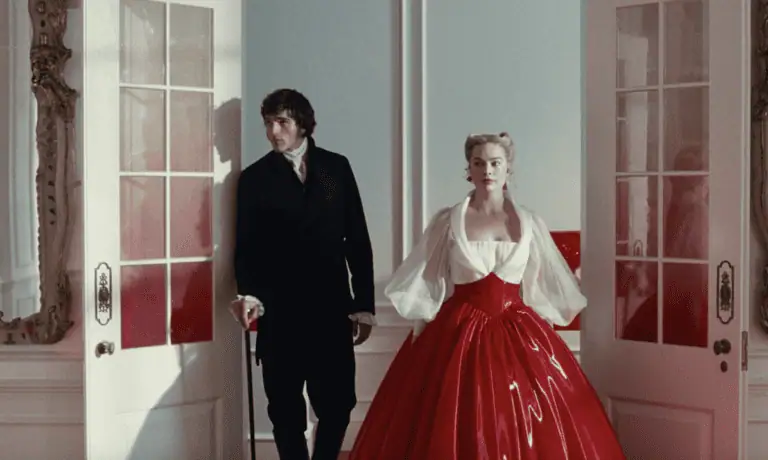 A man in a black suit and a woman in a dramatic red ball gown with sheer white sleeves stand side by side in an ornate room, framed by open white doors—a still from "Wuthering Heights" movie.