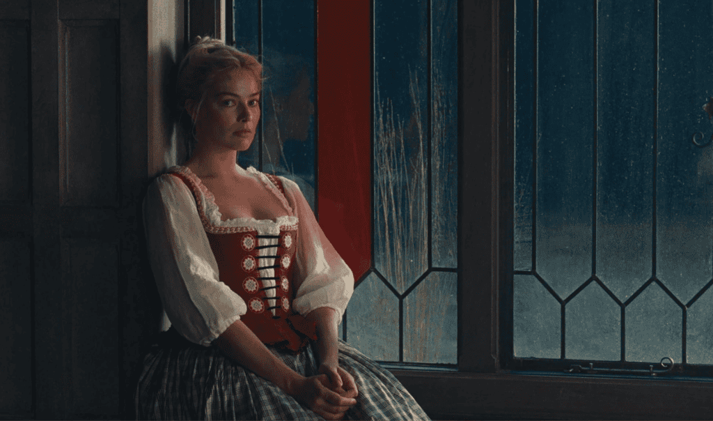 A woman in historical clothing with a red corset and white blouse sits by a large window, looking thoughtful and slightly somber. Soft light filters through the glass, illuminating her face and the wooden paneling behind her.