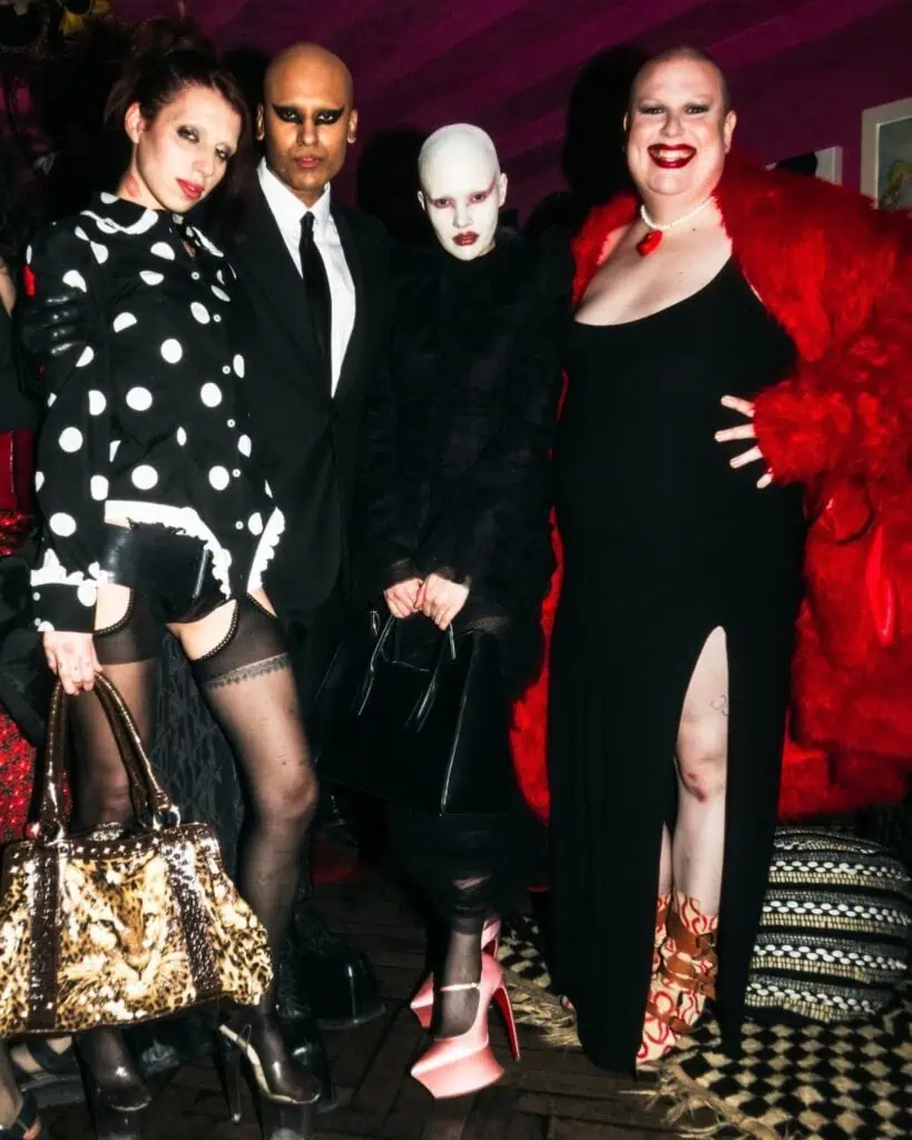Four ndividuals posing together in high-fashion alternative outfits, including polka dots, fur coats, and extreme platform heels, posing at Dahc Dermur VIII event