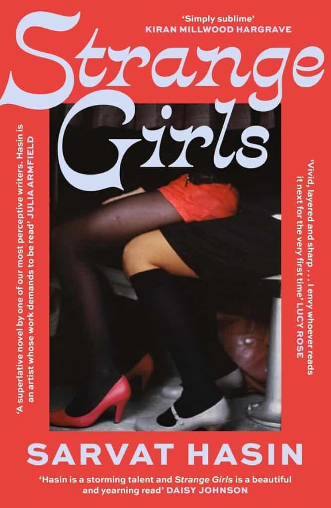 Book cover for Strange Girls by Sarvat Hasin. The image shows a person sitting on a chair, legs crossed, wearing a red skirt, black tights, and black heels. The title is in large, white and yellow script.