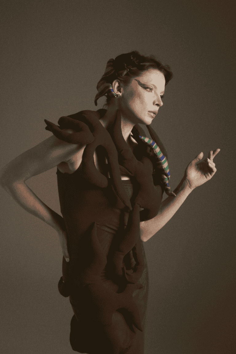 An editorial profile shot of a model wearing a dark No.sugar garment adorned with intertwined fabric "roots," highlighting the brand's focus on organic shapes and Uzbek heritage.