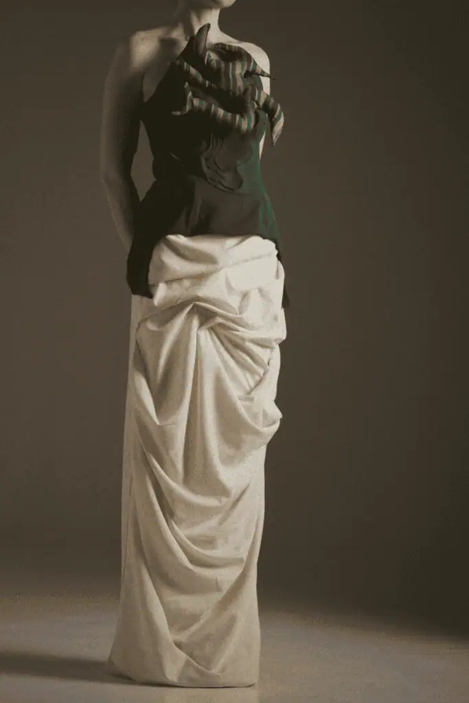 A studio shot of a No.sugar design featuring a dark strapless bodice with striped root accents paired with a voluminous, draped cream-colored floor-length skirt.