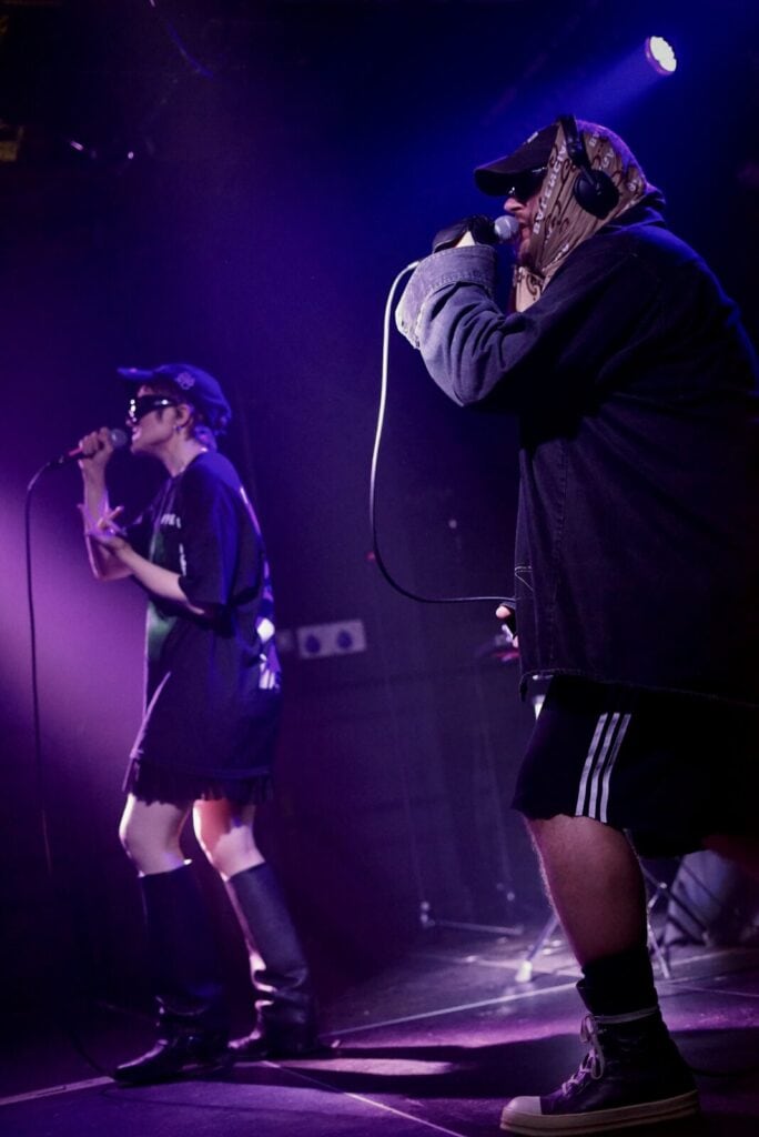 Juuso Malin and Sandra Tervonen of the Finnish duo Pearly Drops performing together under atmospheric purple stage lighting.