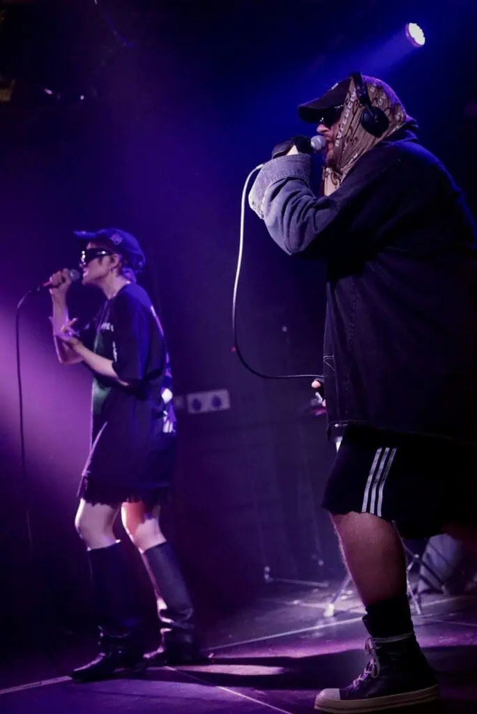Juuso Malin and Sandra Tervonen of the Finnish duo Pearly Drops performing together under atmospheric purple stage lighting.