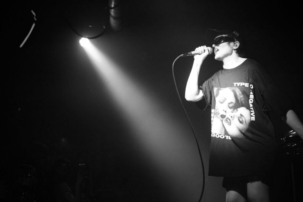 Sandra Tervonen singing into a microphone during a Pearly Drops set, showcasing the duo's grungy and vulnerable live musical style.