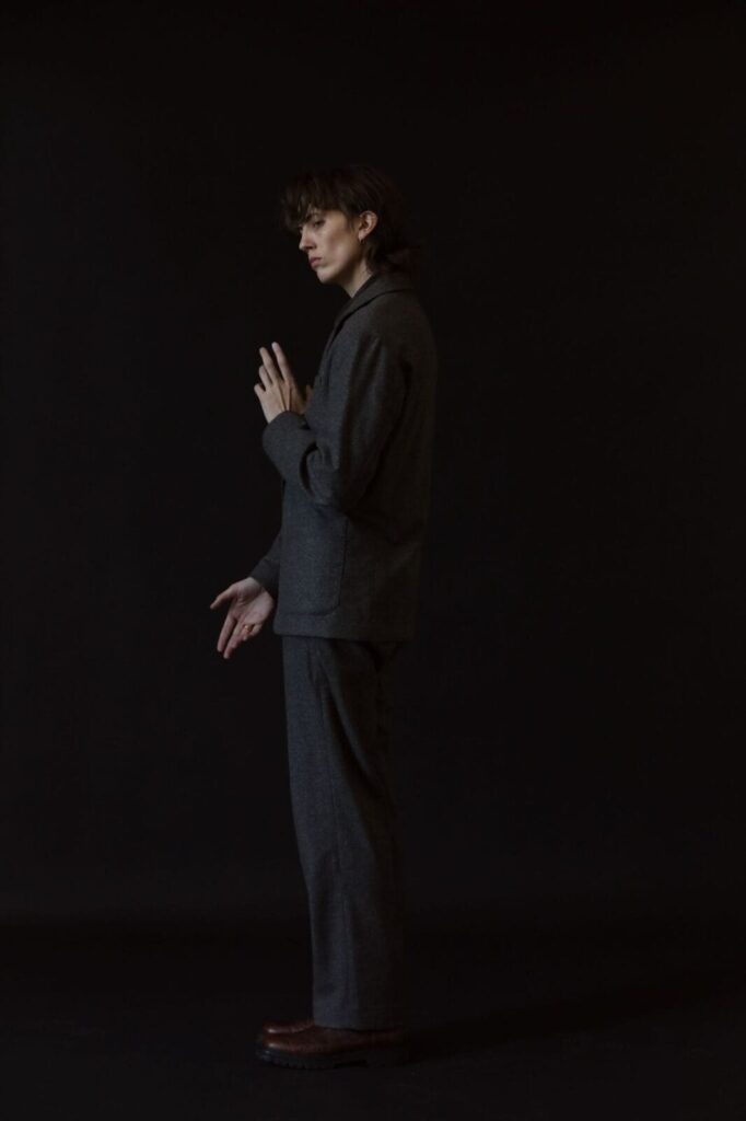 E.R. Fightmaster posing in a grey suit against a solid black background