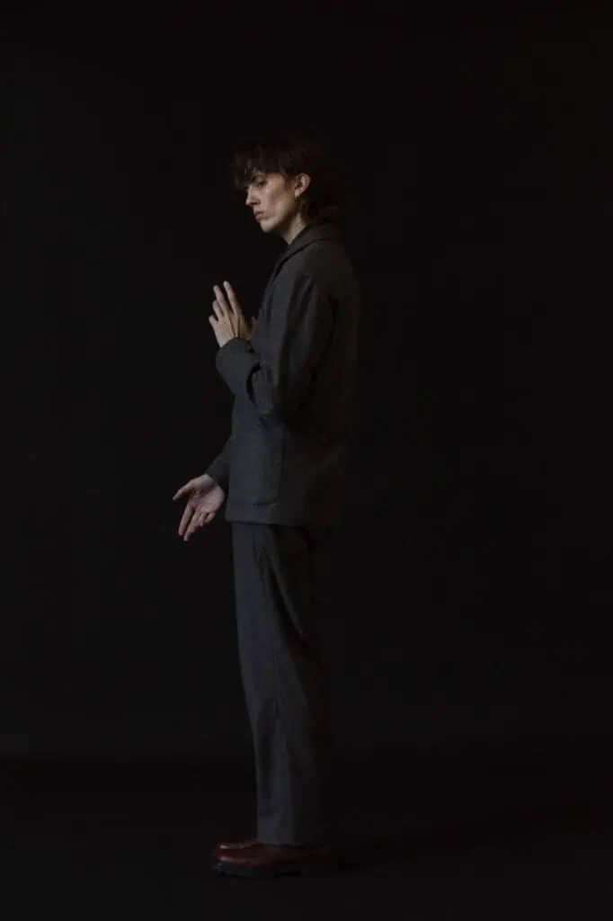 E.R. Fightmaster posing in a grey suit against a solid black background