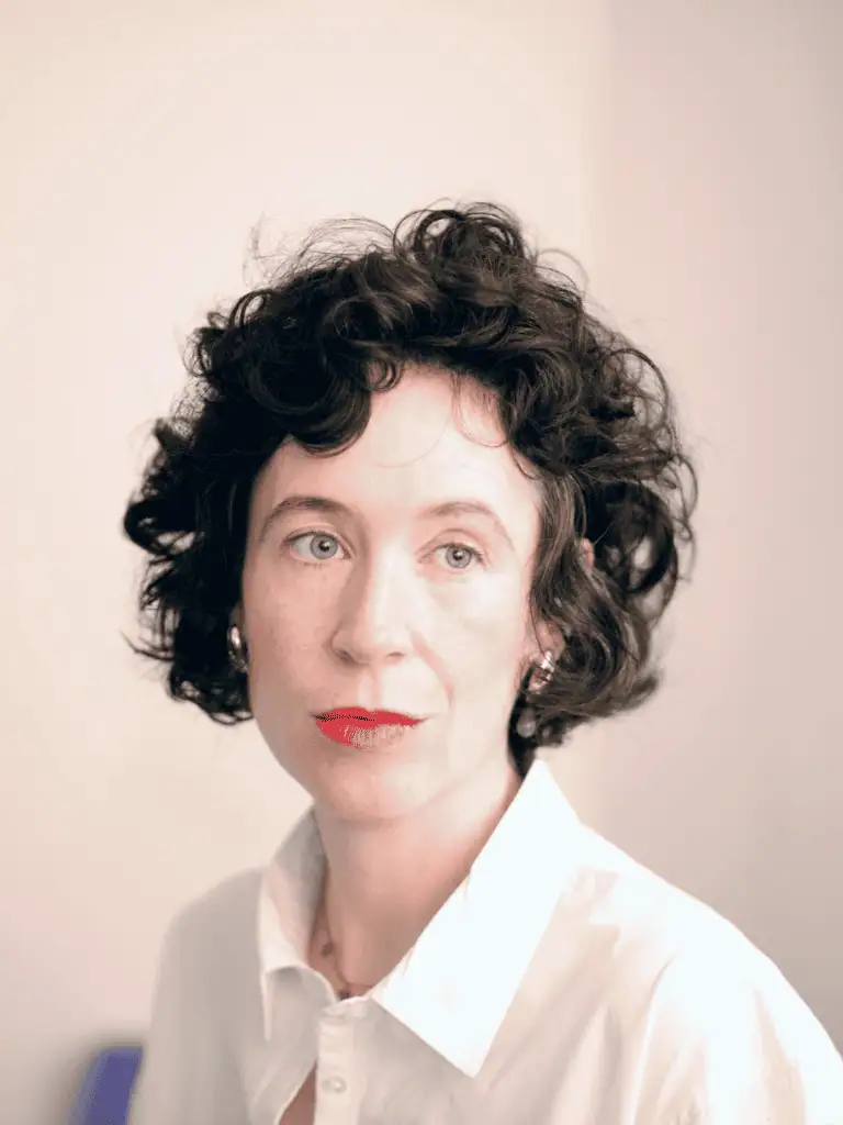 Close-up portrait of Niamh Campbell with dark curly hair and a white shirt