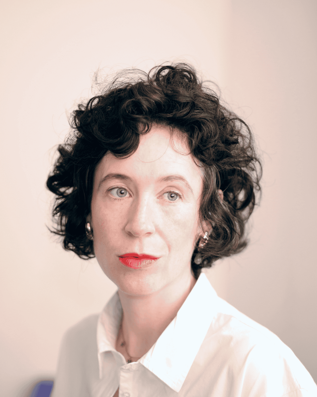 Close-up portrait of Niamh Campbell with dark curly hair and a white shirt